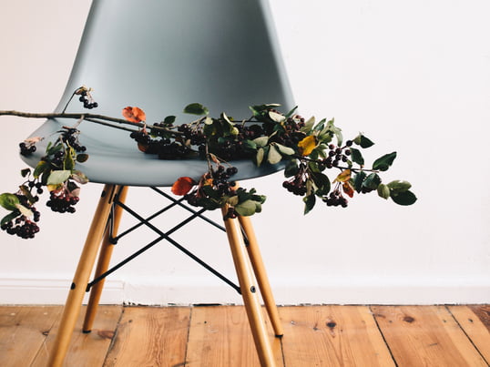 Laetitia Delorme von Monochrome DIY setzt auf ihrem schönen Dielenboden den Eames Plastic Side Chair DSR in der Farbe Ocean von Vitra mit einem Strauß Beeren in Szene.