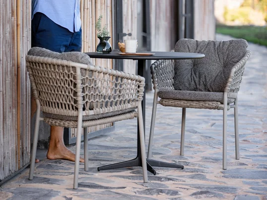 Ocean Armlehnstuhl, taupe von Cane-line in der Ambienteansicht. Eine gewölbte Rückenlehne und Armlehnen bieten einen angenehmen Komfort, sodass sich gemütliche Stunden in dem Stuhl verbringen lassen.