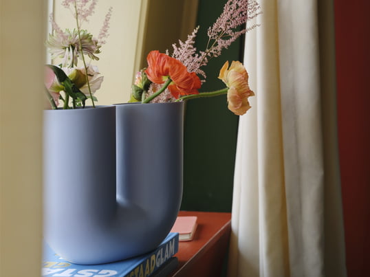 Die Kink Vase von Muuto in der Ambienteansicht: Durch die gebogene Form der Vase entstehen zwei Öffnungen, in denen einzelne Blüten und Blumen dekorativ angeordnet werden können.