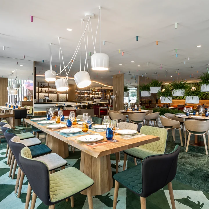 Die AIM LED-Pendelleuchte von Flos über den Tischen in einem Restaurant