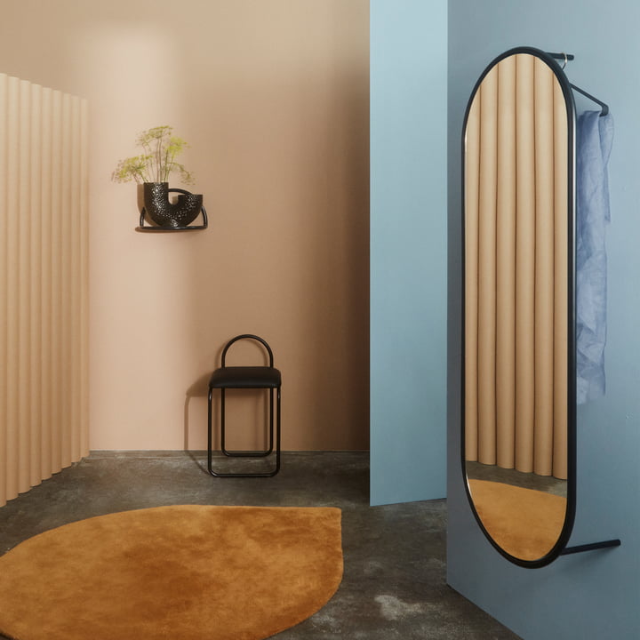 Der Angui Wandspiegel von AYTM an einer blauen Wand in der Garderobe