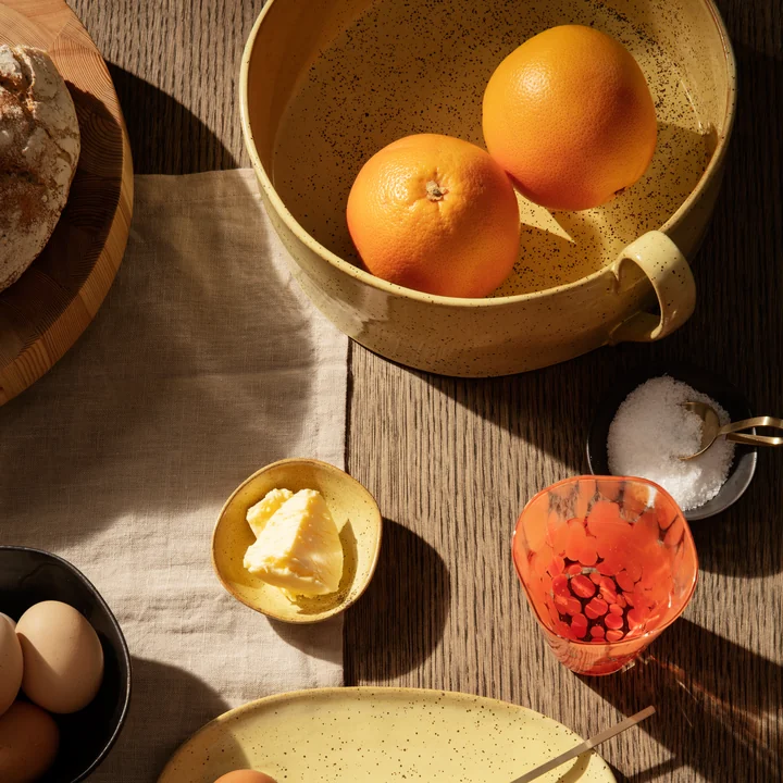 Die Flow Obstschale von Ferm Living auf dem gedeckten Frühstückstisch mit Orangen, Brot und Butter