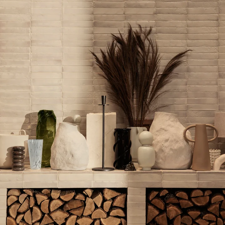 Die Vulca Vase von Ferm Living neben weiteren Vasen und Kunstobjekten auf einer Steinbank