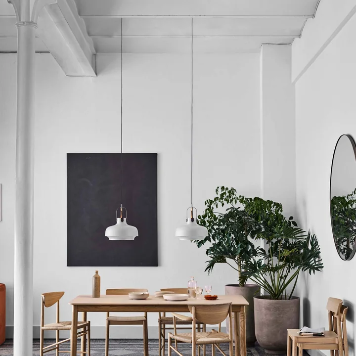Der Amore Spiegel rund von &Tradition in einem hellen Esszimmer mit hohen Decken und einem hellen Holz-Esstisch