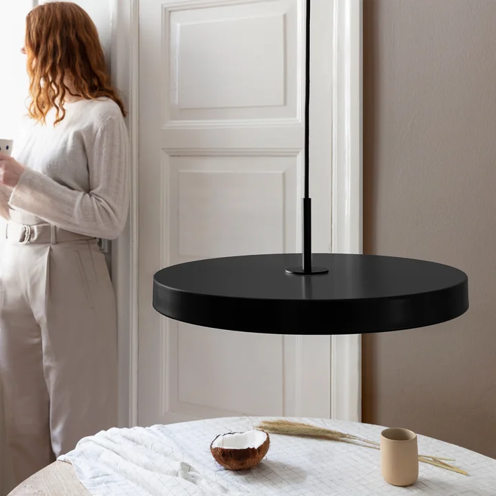 Die Asteria LED-Pendelleuchte von Umage in schwarz / schwarz über einem runden, weißen Esstisch