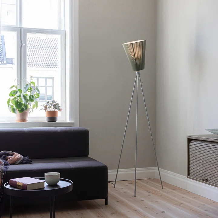 Die Oslo Wood Stehleuchte von Northern im Wohnbereich neben einem dunklen Sofa