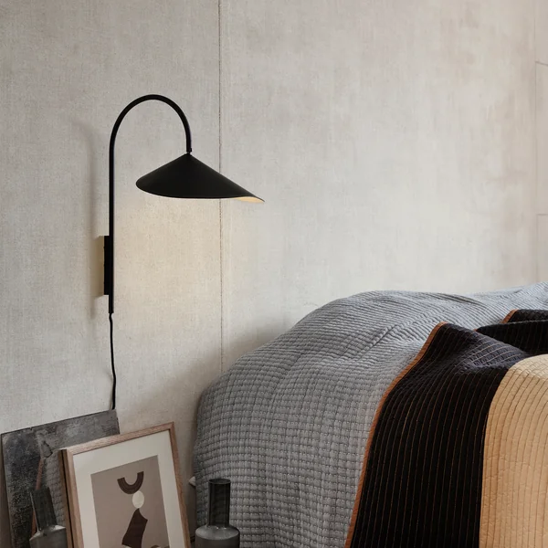 Arum Wandleuchte in schwarz von Ferm Living neben dem Bett